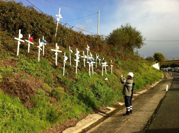 El colectivo situó cruces y cascos en el talud de la autopista recordando a los despedidos (foto: Raúl Salgado)
