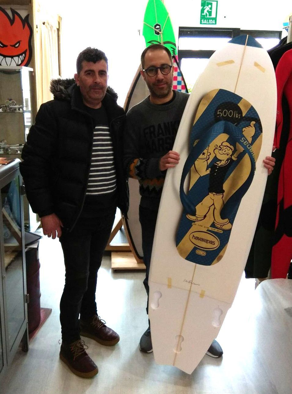 Vito y Miguel posan con la tabla, que está expuesta en Crest hasta este viernes (cedida)